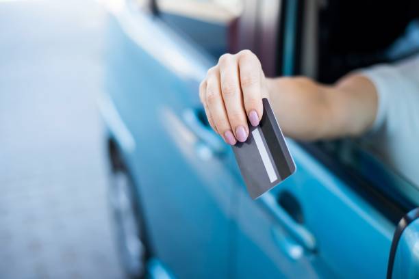 A woman pays with a credit card while refueling a car