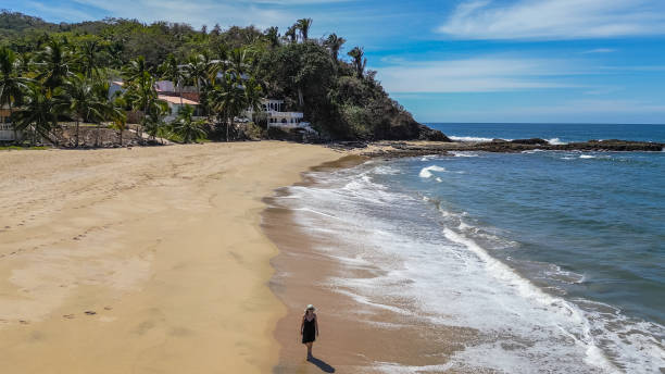 istock Aerial view of woman walking along empty beach 2157594408