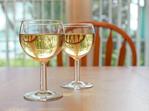 istock Two Chardonnay filled wine glasses on dinging room table back lit by window light 2157595530