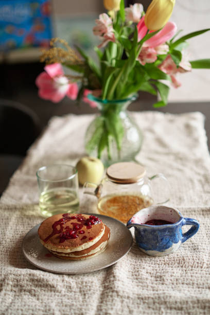 istock Simple pancake breakfast with jam and apple, tea served on a kitchen table 2157605137