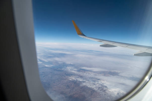 Aircraft wing over snowcapped mountains. Aerial view.