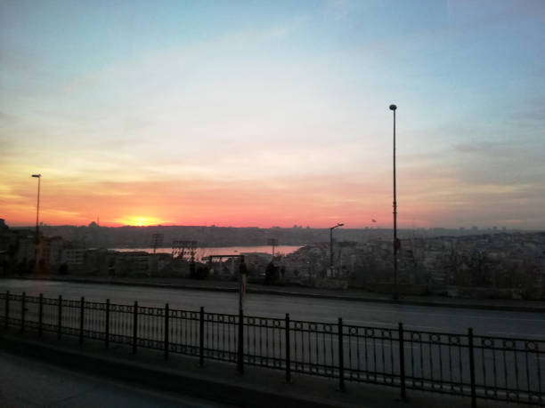 A hazy sunrise over the densely packed skyline of Istanbul, Turkey, highlights the impact of rapid urbanization, city noise, and air pollution. The image captures the sprawling metropolis with layered high-rises and smoggy skies, reflecting the challenges of overpopulation and environmental stress in modern megacities. Ideal for themes related to urban development, climate issues, population density, and metropolitan life.