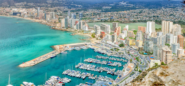 Soar above Calpe with this panoramic view of its urban shoreline, where the sea meets skyscrapers. Discover a city buzzing with life, poised on the brink of the Mediterranean, in a photograph that encapsulates both the energy of the city and the tranquility of the sea.