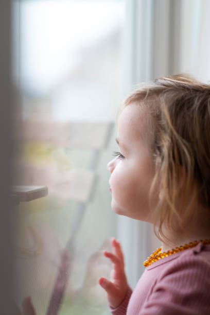 istock little girl looking outside 2157612816