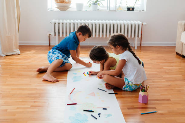 istock Creative children sitting on the floor and drawing with crayons on a paper 2157613392