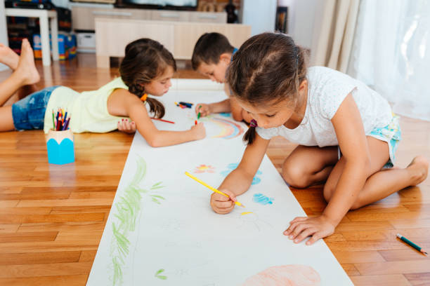 istock Children having fun drawing with crayons on a paper on the floor 2157613866