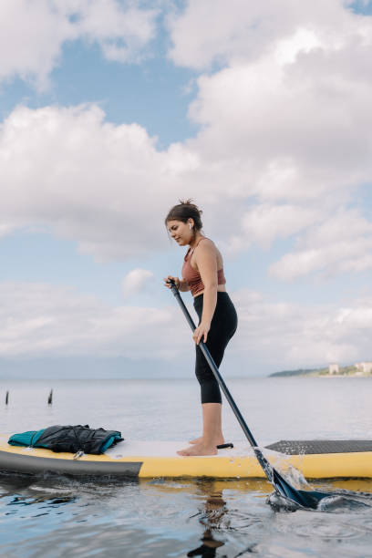 istock A woman is standing on a surfboard in the water 2157622669
