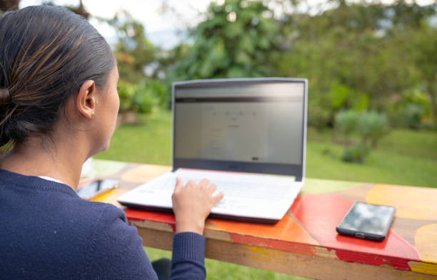 istock Young Woman working outdoors and studying online and taking virtual classes during a sunny day with a laptop and a smartphone focus on working and her mobile 2157623878