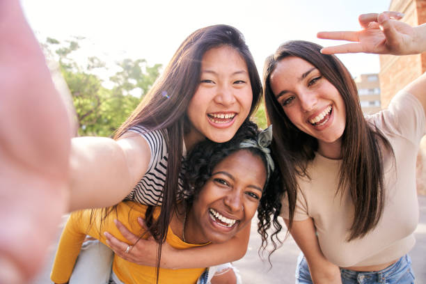 istock Group young multi-ethnic female taking smiling selfie portrait together outdoors. Excited friends. 2157624000