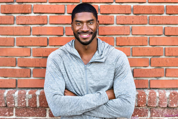 istock Cheerful man standing by a red brick wall 2157637336