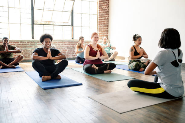 istock Trainer and her students in a Pranamasana pose 2157637366