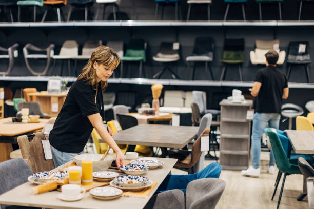 istock Two salespeople in a store arrange dining room tables and chairs on display 2157643418