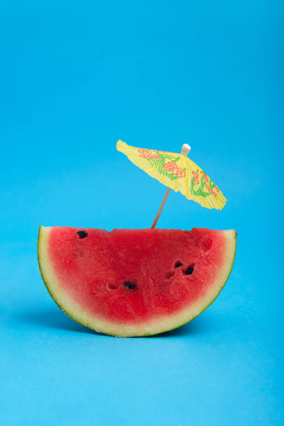 istock Watermelon slice with cocktail umbrella on blue background. Summer background. 2157646717