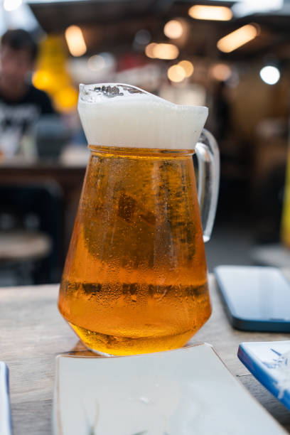 istock Full pitcher of beer on wooden table with blurred background 2157651099