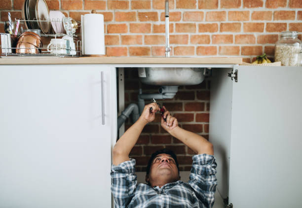 istock Plumber lying on the floor fixing a kitchen sink 2157651486