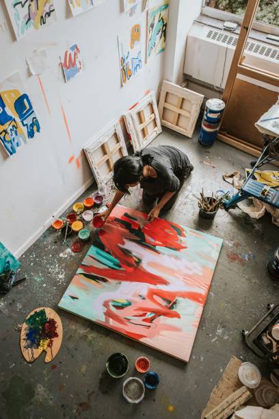 Woman artist working on her paint canvas in her studio