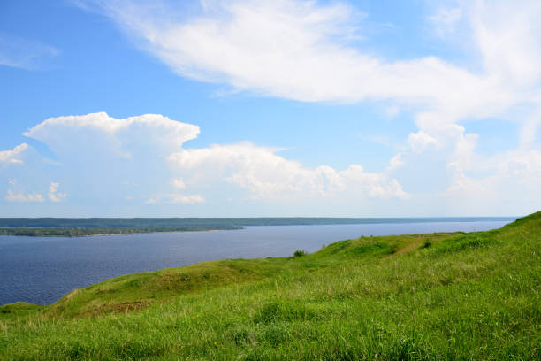 istock a grassy hill with a lake in the background and a blue sky with clouds 2157659963