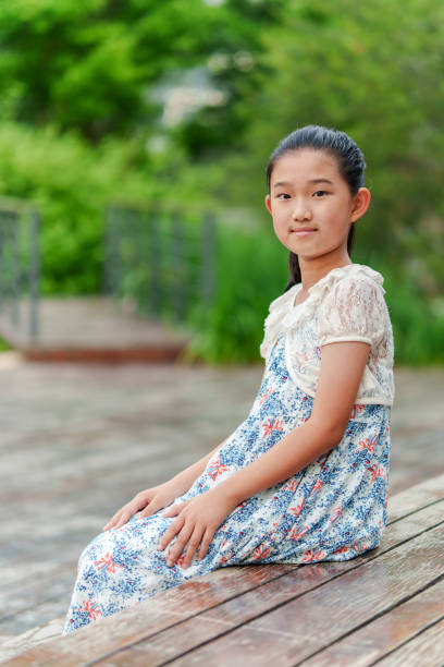 Smiling Asian girl in vibrant red festive traditional dress with matching hair accents, isolated white background. Her joyful expression embodies holiday celebration, Chinese New Year