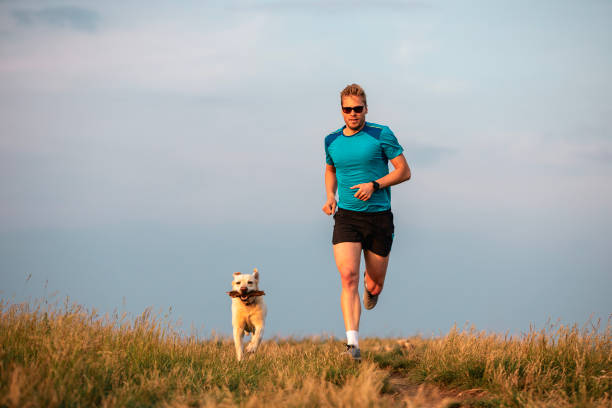 istock Front view of athletic man running with dog 2157664381