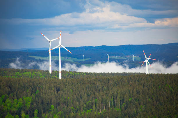 wind turbines in the mountain forest with a low fog under the trees
