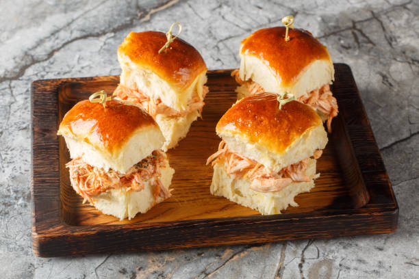 Butter Hawaiian rolls baked with pulled chicken and cheese close-up on a wooden board. Horizontal