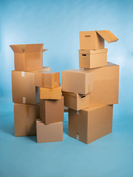 istock Carton boxes. Parcels are stacked on top of each other. Boxes for packing orders from online store. Many parcels of different sizes on turquoise. Open and closed boxes without inscriptions 2157673461
