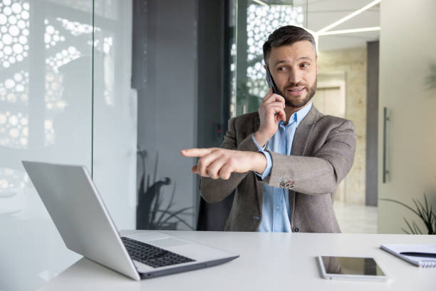 istock Businessman pointing while talking on the phone in office 2157673709