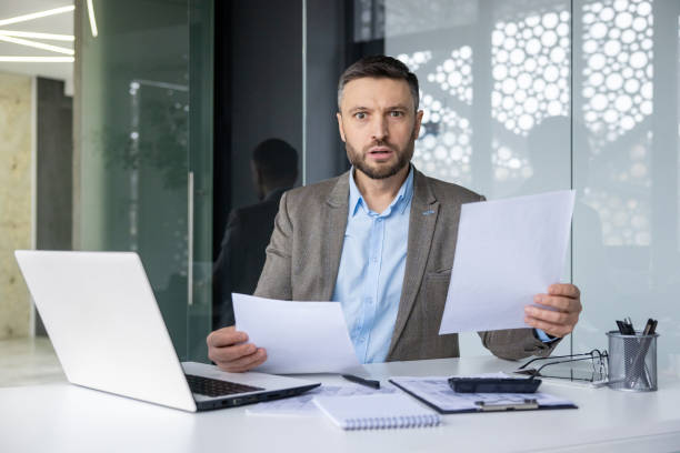 istock Surprised businessman reading documents at his desk in modern office 2157674153