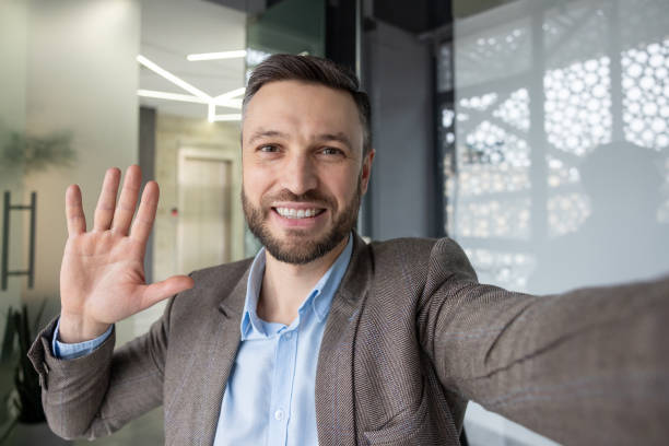 istock Smiling businessman waving during a video call on smartphone 2157675101