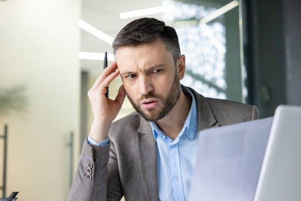 istock Confused businessman reading a document while working on laptop in office 2157675230