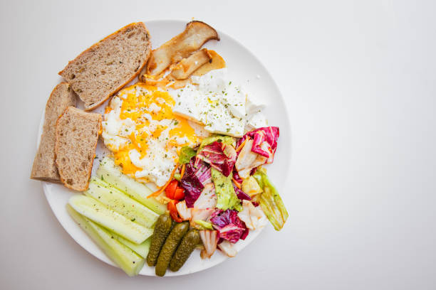Healthy vegetarian breakfast with eggs, cherry tomatoes, cucumbers, pickles, parsley, and cheese in beautiful natural light