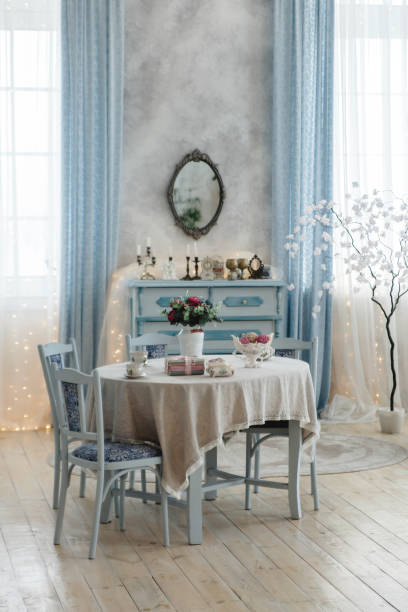 istock Beautifully decorated dining space featuring a vintage table with lace tablecloth, blue chairs, and floral centerpiece. Antique dresser and mirror enhance the room's elegant appeal 2157680301
