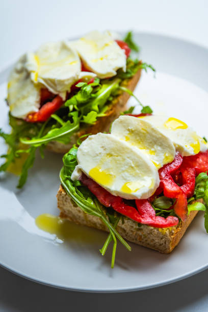 Healthy vegetarian sandwich with mozzarella, pesto, arugula, beefsteak tomato, drizzled with olive oil, on sourdough bread. Beautiful natural light