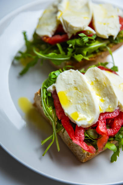 Healthy vegetarian sandwich with mozzarella, pesto, arugula, beefsteak tomato, drizzled with olive oil, on sourdough bread. Beautiful natural light