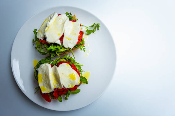 Healthy vegetarian sandwich with mozzarella, pesto, arugula, beefsteak tomato, drizzled with olive oil, on sourdough bread. Beautiful natural light