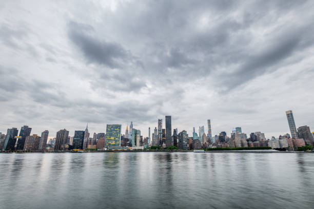New York City lower Manhattan skyscrapers between clouds with a moody dark sky at dusk