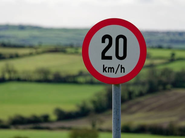 istock A red and white 20 km/h speed limit sign stands against a blurred green backdrop, indicating a traffic regulation in a verdant area. 2157689910
