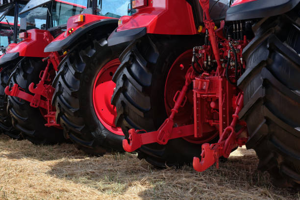 istock Rear view of several large modern red tractors standing in a field. 2157694841
