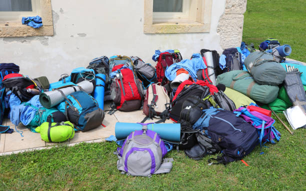 many backpacks and sleeping bags belonging to young adventurous backpackers during summer camping