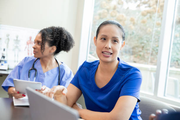 istock Engaged in dialogue, a female medical professional dressed in blue scrubs communicates with her coworker during a staff conference. 2157710854