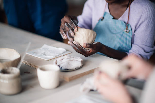 istock Close up of diverse attendee's hands shaping clay at pottery class. 2157711282