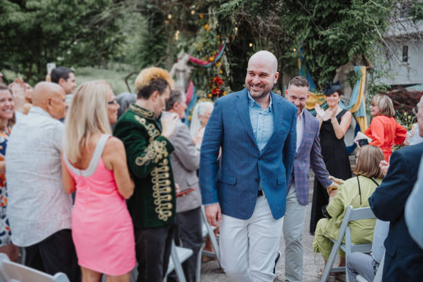Excited gay couple after wedding ceremony Smiling gay couple holding hands and walking through crowd of guests after their outdoor wedding ceremony. gay wedding kiss stock pictures, royalty-free photos & images