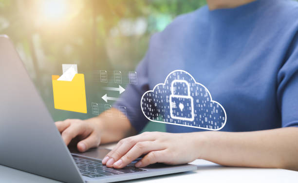 person managing secure cloud data transfer. an individual uses laptop to manage secure data transfer to cloud, virtual lock, representing robust cybersecurity measures. file storage, manage folders, - versleuteling stockfoto's en -beelden