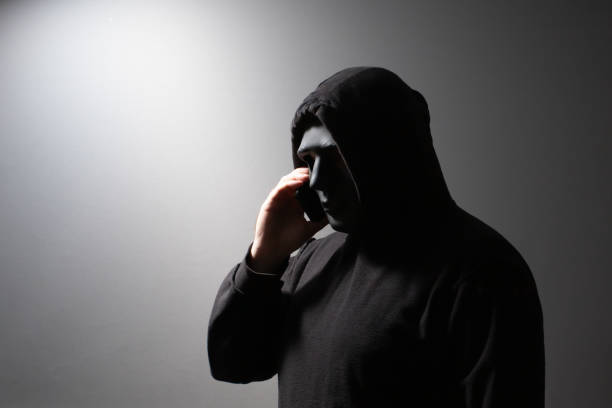 istock Phone Scammers, man in a mask with a phone, cyber criminal stealing information, hacker attacking accounts, online theft and fraud 2157717226