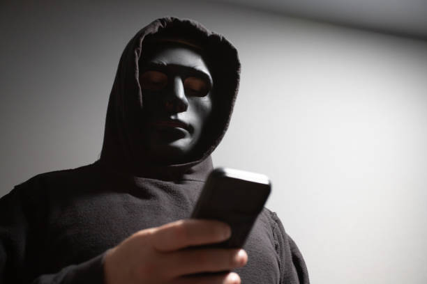 istock Phone Scammers, man in a mask with a phone, anonymous hacker performing phishing, identity theft via mobile phone, danger to privacy and security 2157717237
