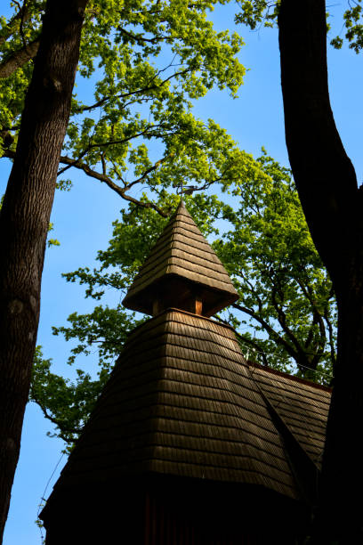 Wooden church tower stands tall, surrounded by lush green trees.