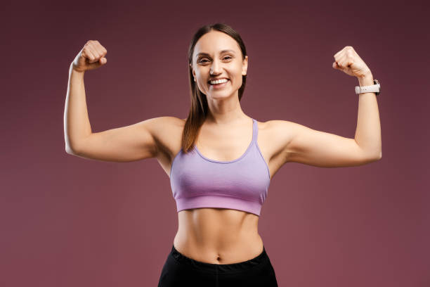 istock Happy Caucasian young woman showing biceps on her hands posing in studio, isolated 2157718420