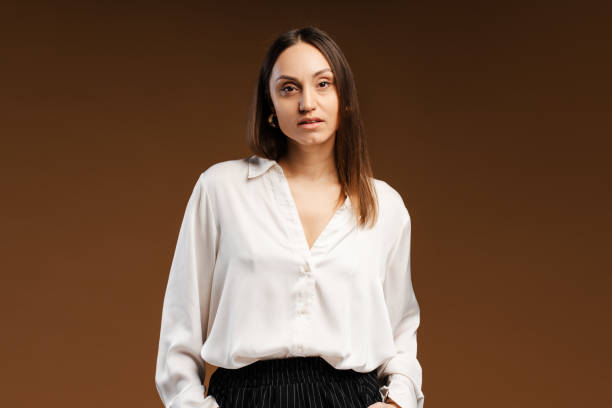 istock Calm young woman in white shirt looking at camera posing in studio, isolated 2157718586