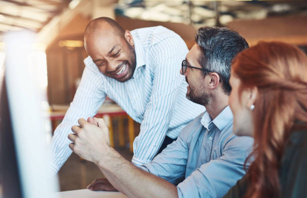 istock Business people, computer and help with teamwork, mentor and funny with joke, laughing and humor. Staff, employees and coaching with pc, cooperation and collaboration with advice, ideas and planning 2157718995