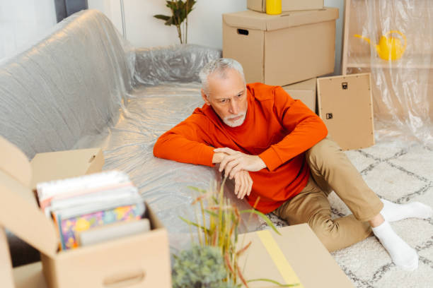 istock Upset tired mature man sitting on floor feeling exhausted preparing unpacking cardboard boxes 2157719175